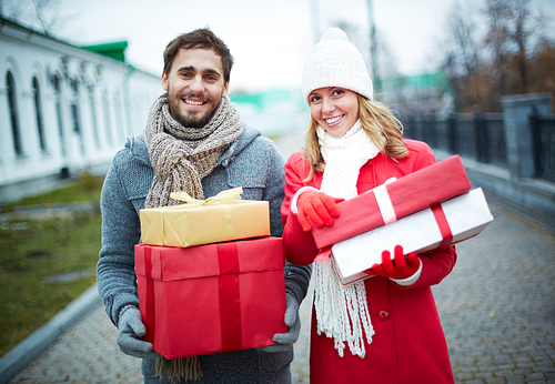 Happy young man and woman holding Christmas gifts