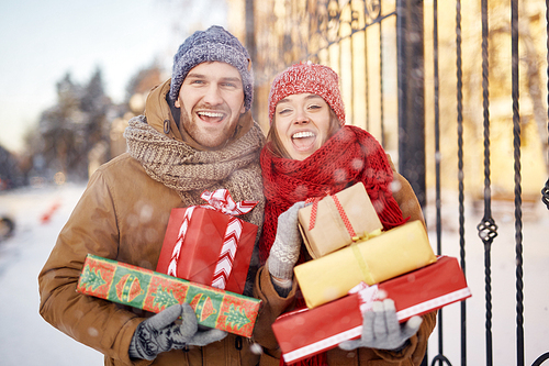 Young ecstatic couple with gift-boxes  outdoors