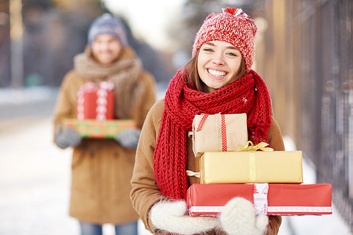 Happy young woman with presents  with toothy smile on background of her boyfriend