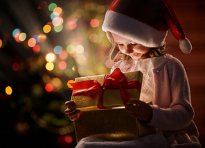 Happy girl in Santa cap looking at wonderful Christmas present in giftbox