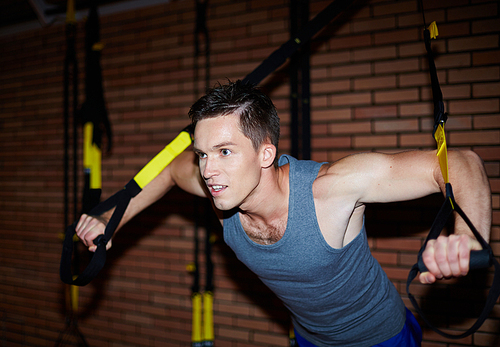 Young man in activewear doing exercises for arm muscles