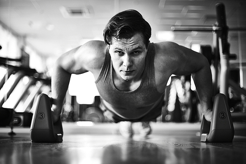 Handsome athlete doing difficult exercise in gym