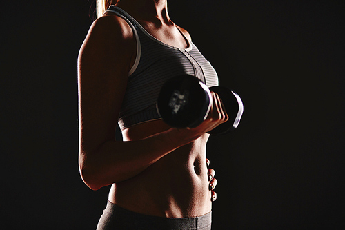 Female in activewear doing exercise with dumbbell