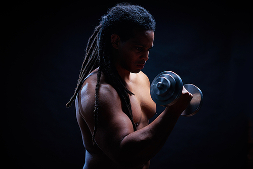 Muscular man with dreadlocks exercising in gym