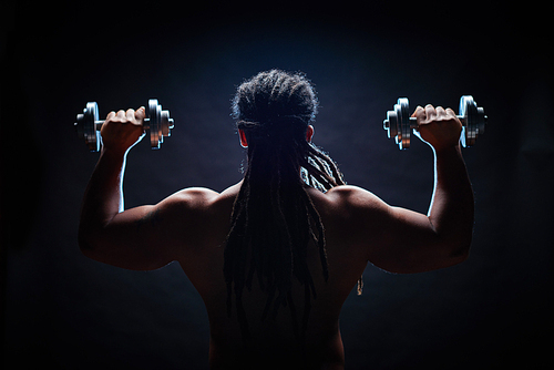 Back view of muscular man with dreadlocks training in gym