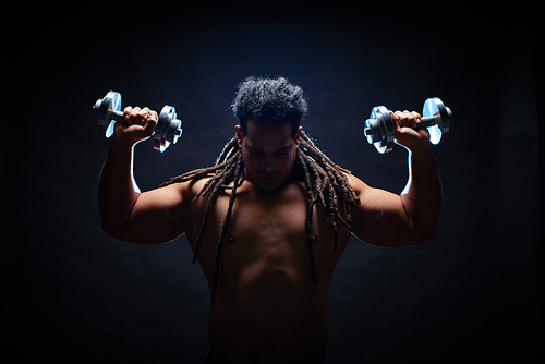 Strong man with dreadlocks working out in gym