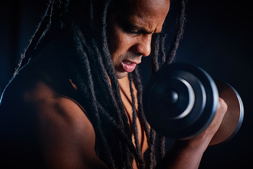 Young sporty man with barbell pumping arm muscles