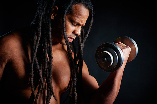 Topless young athlete with dreadlocks exercising with barbell