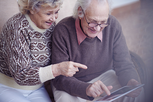Elderly husband and wife using digital tablet at home