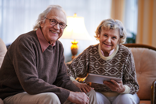 Smiling senior man  on background of his wife with touchpad