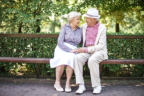 Happy senior couple talking while sitting on bench