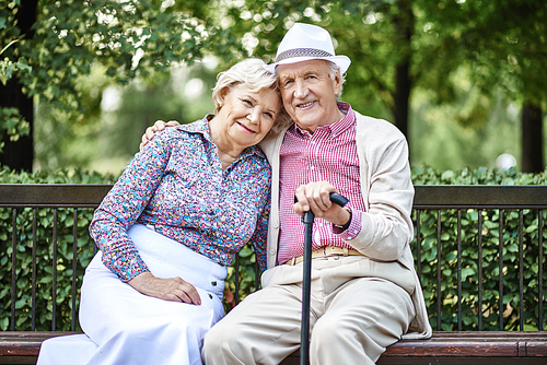 Smiling senior couple sitting on bench in the park