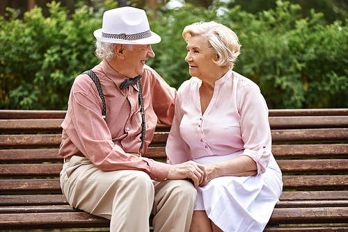 Romantic seniors in smart casual relaxing in park and talking