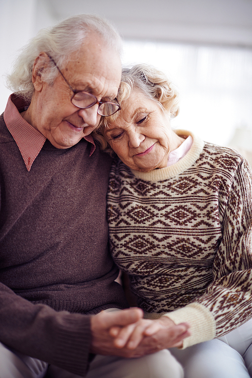 Devoted couple of pensioners in sweaters holding by hands