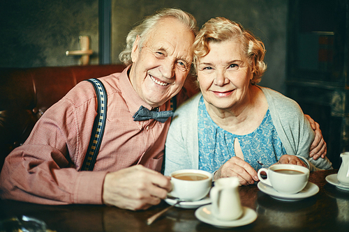 Happy retired couple having tea in cafe