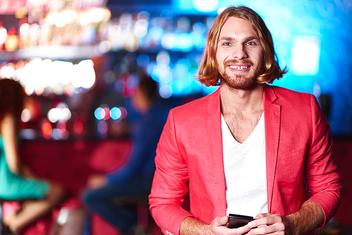 Happy young man in white V-shirt and red jacket  in night club
