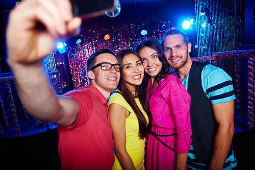 Group of happy friends making selfie in nightclub