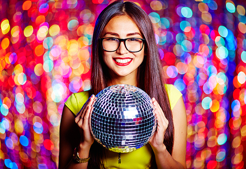 Posh female with toothy smile holding disco ball
