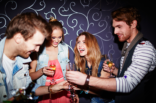 Cheerful friends with flutes of champagne spending time in nightclub