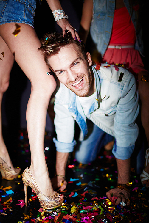 Handsome guy by legs of girl having fun in night club