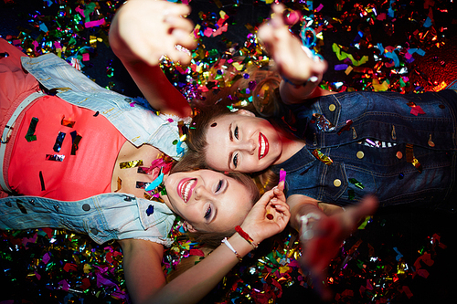Two energetic girls with raised arms  in nightclub