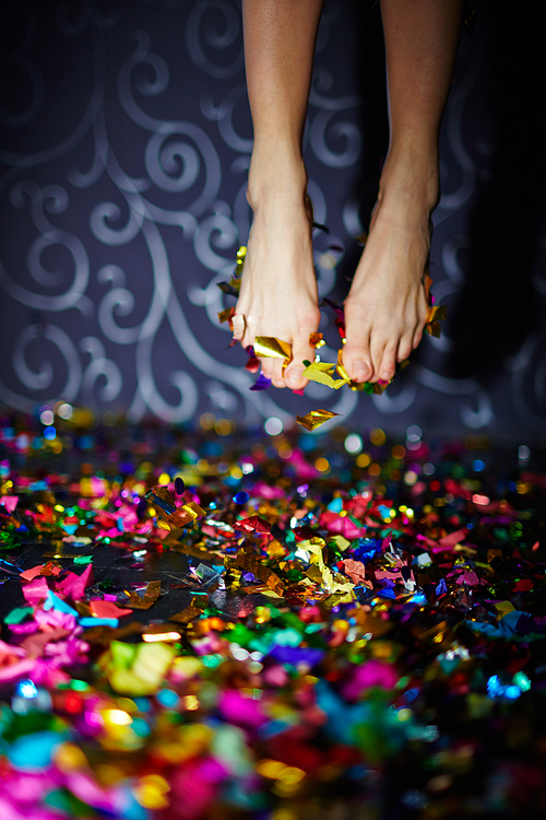 Female feet in jump over floor with confetti