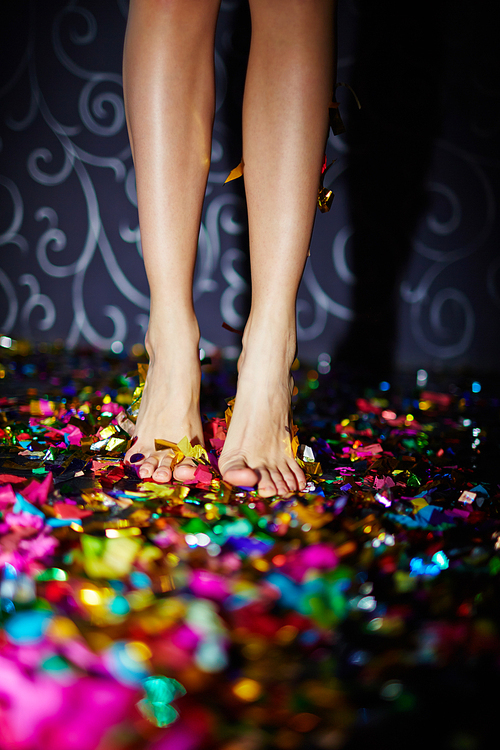 Barefoot female standing on the floor with confetti