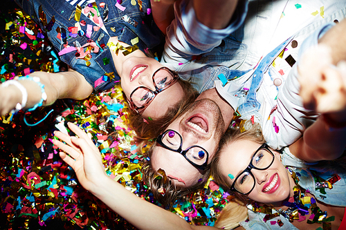 Three smiling friends making selfie while lying on the floor in nightclub