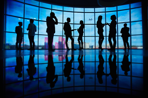 Outlines of business people communicating at meeting against window