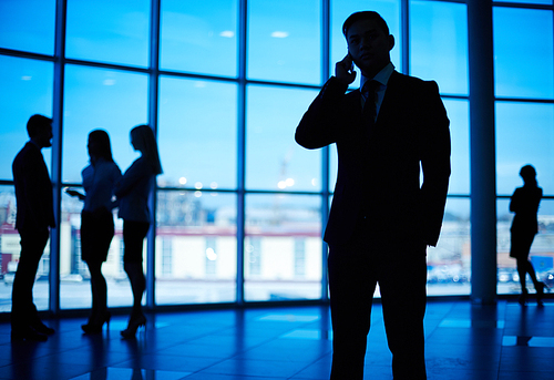 Businessman in suit speaking on the phone in modern office