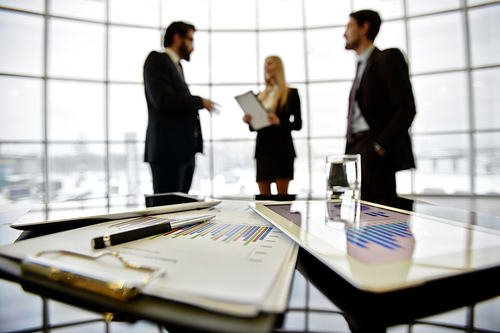 Close-up of papers and touchpad on table against managers