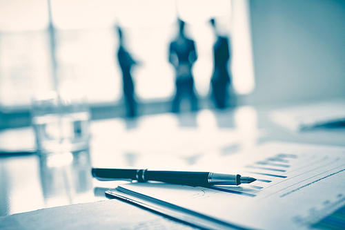 Fountain pen on business document, three men standing on background