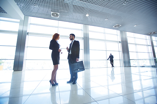 Two colleagues communicating in corridor