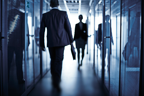 Silhouettes of business people walking along corridor of office building