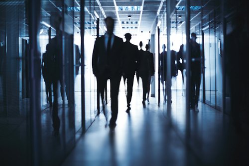 Silhouettes of business people going down office building corridor