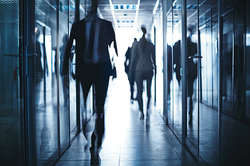 Blurred silhouettes of business people moving in corridor