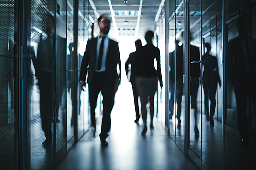 Busy employees going down office building corridor