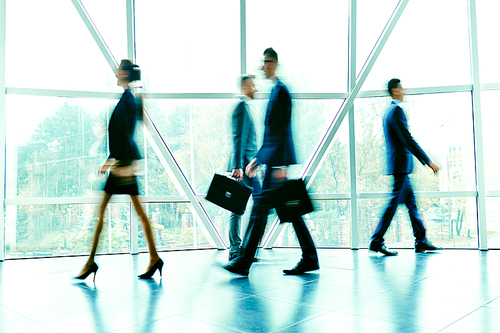 Blurred figures of hurrying employees inside office building