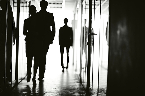 Outlines of business people walking along corridor of office center