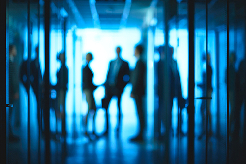 Silhouettes of co-workers interacting in corridor of office center