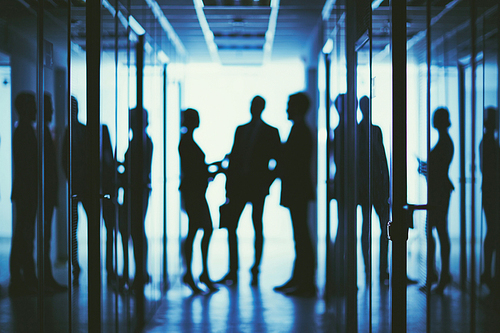 Blurred silhouettes of group of managers interacting in office center