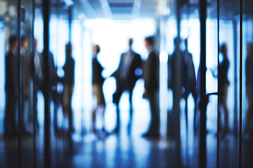 Silhouettes of business partners interacting in corridor of business center