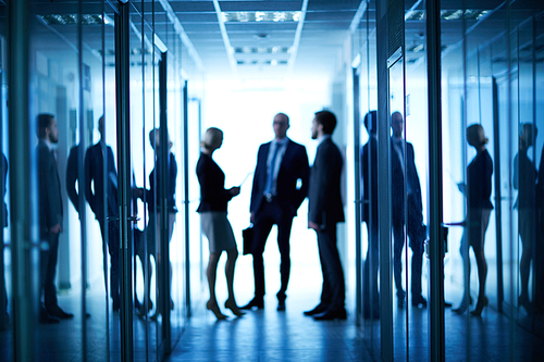 Group of co-workers interacting in corridor between offices