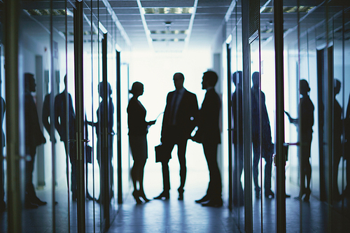 Blurred silhouettes of business people having meeting in corridor of office center