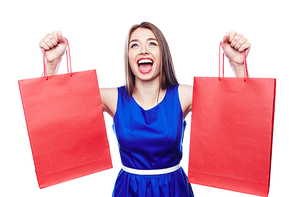 Ecstatic shopaholic with red paperbags in raised hands expressing triumph