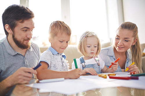 Kids and their parents with crayons drawing together at home