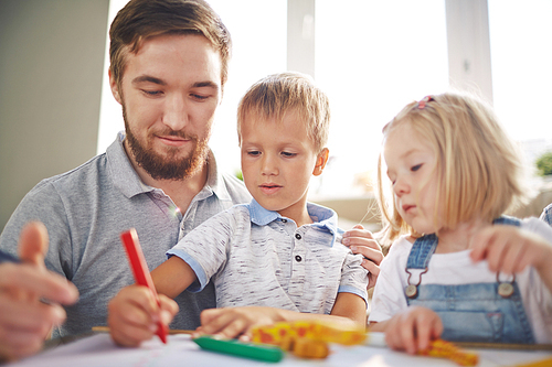Cute children and their father drawing together at home