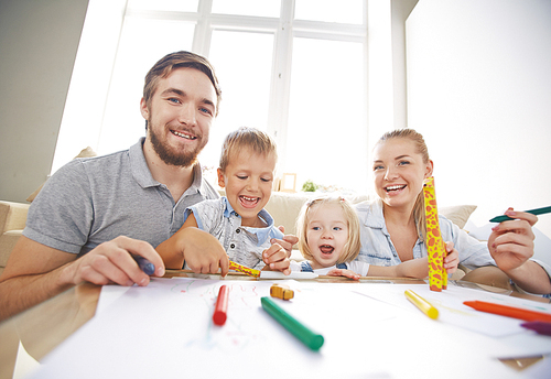 Happy couple with two children drawing at home