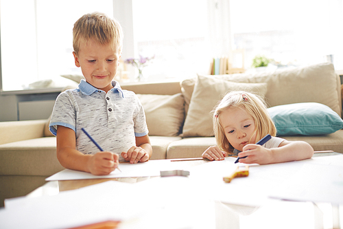 Adorable siblings drawing together at home