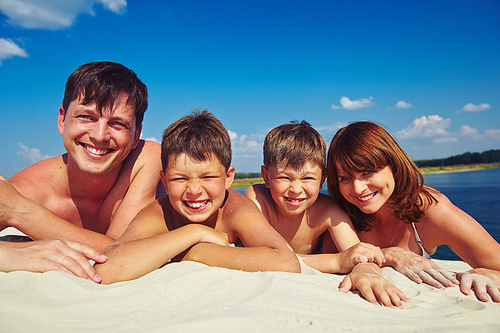Happy family sunbathing on sandy beach